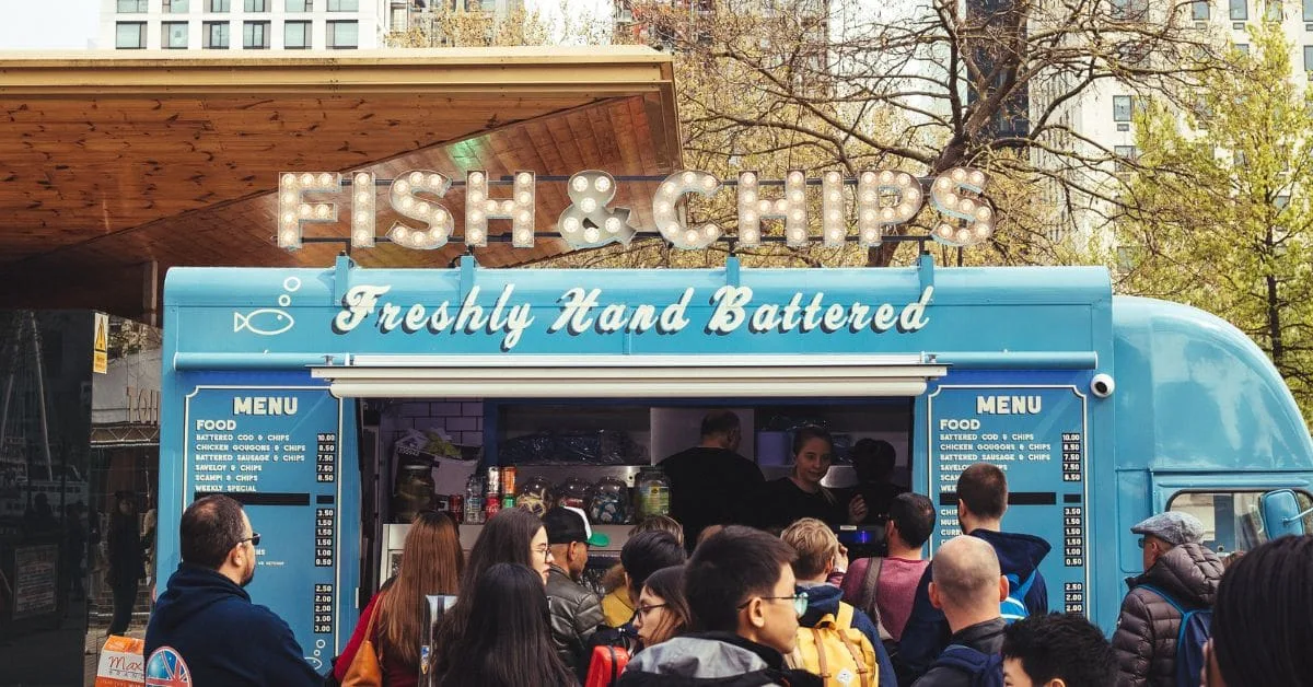 Crowd gathering at a traditional fish and chips stall in London, highlighting a popular British culinary experience.
