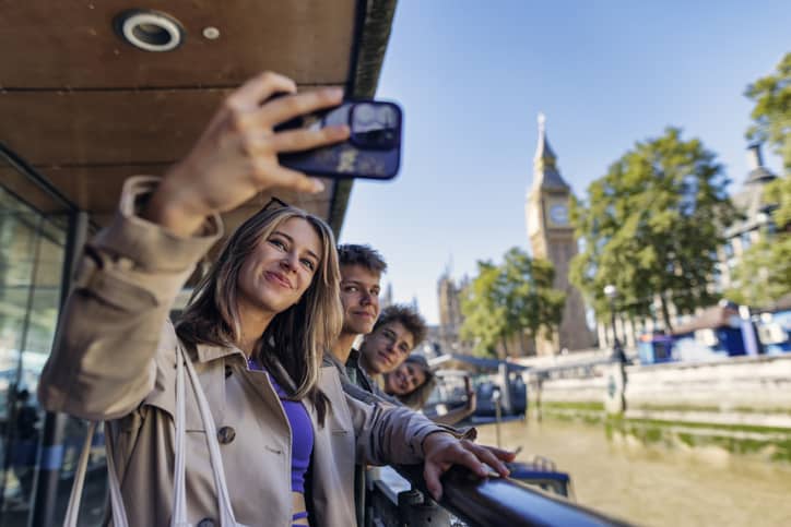 Mother and three teenage kids have been travelling by boat in London, United Kingdom. They have disembarked near the Westminster bridge and the Big Ben. Summer vacations day. They are taking selfies. Shot With Canon R5
