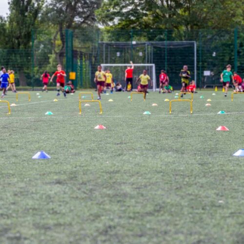School children running on a football field during sports.